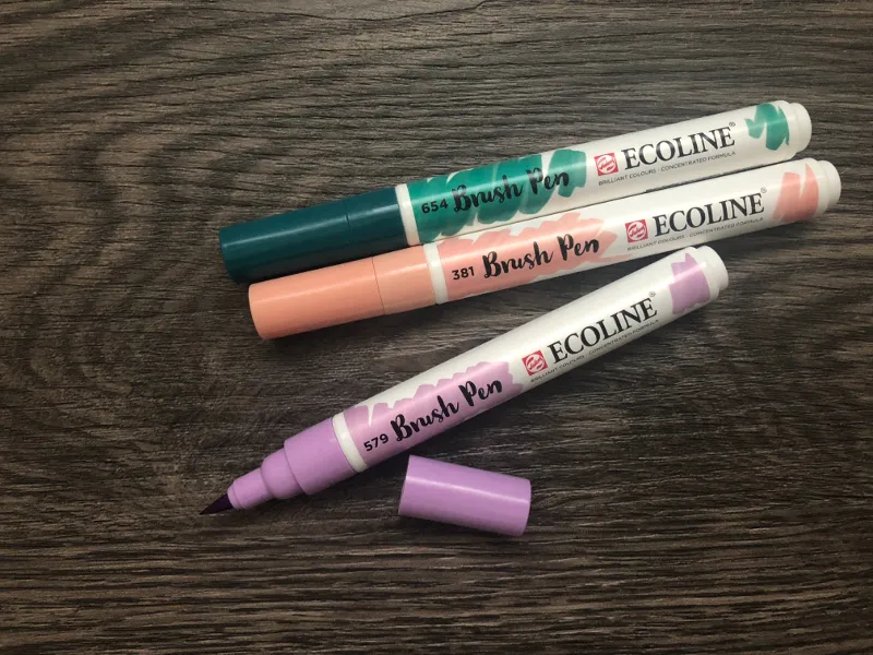 Drei Ecoline Brush Pens in Dunkelgrün, Apricot und Flieder, einer mit offener Kappe