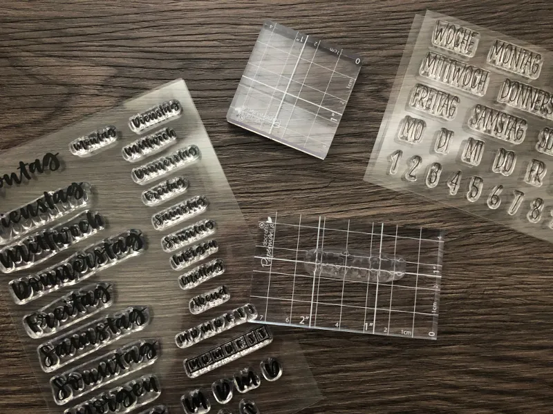 Klare Stempel mit Wochentagen und Zahlen sowie Positionierungshilfen auf Holztisch