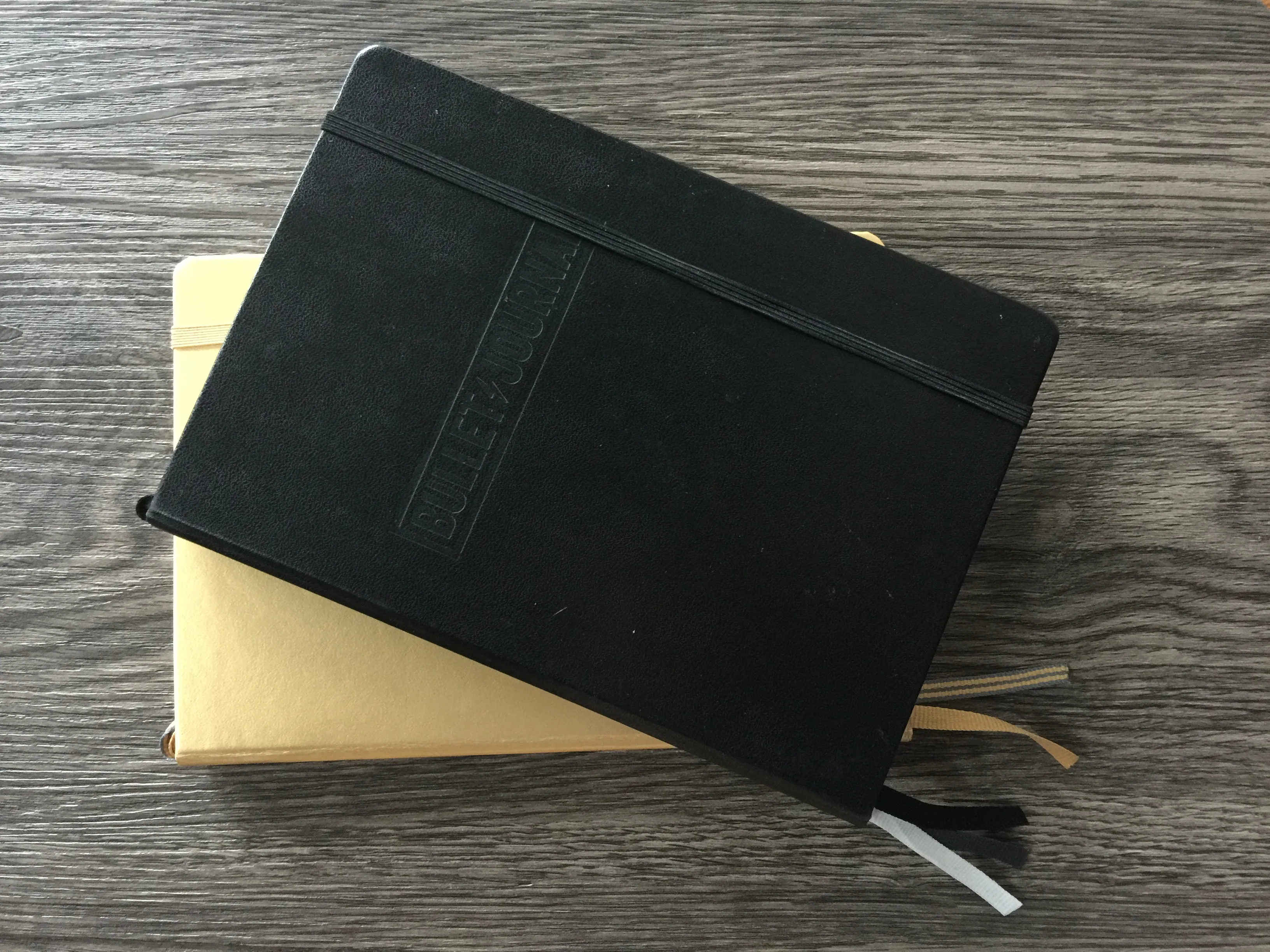 Schwarzes Bullet-Journal-Notizbuch liegt auf einem gelben Notizbuch
