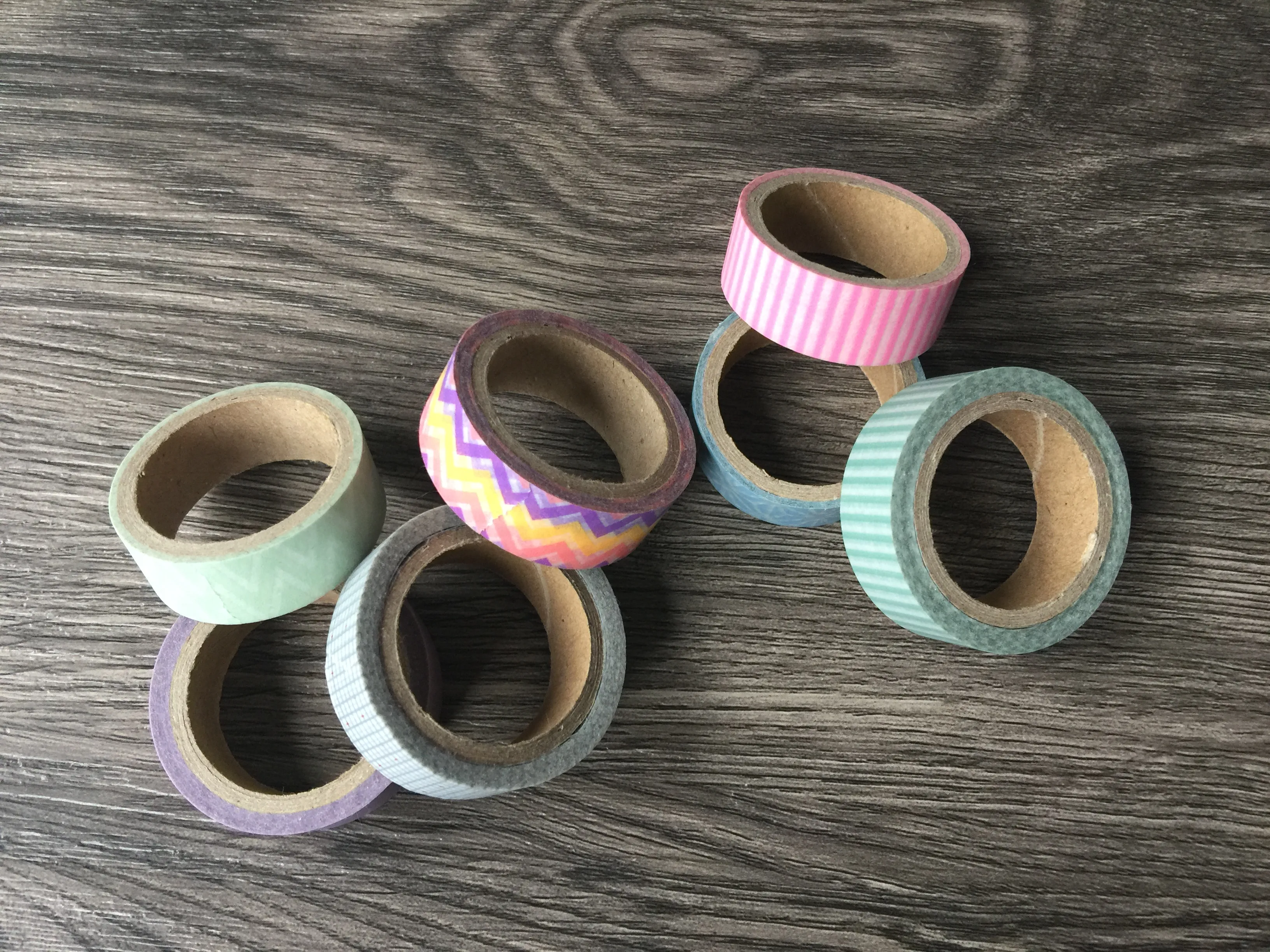Mehrere Rollen Washi Tape in pastelligen Mustern auf Holztisch