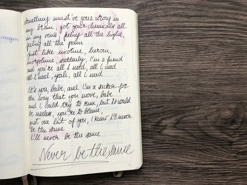 Handschriftlicher Songtext in blauer Tinte mit Schriftzug Never be the same