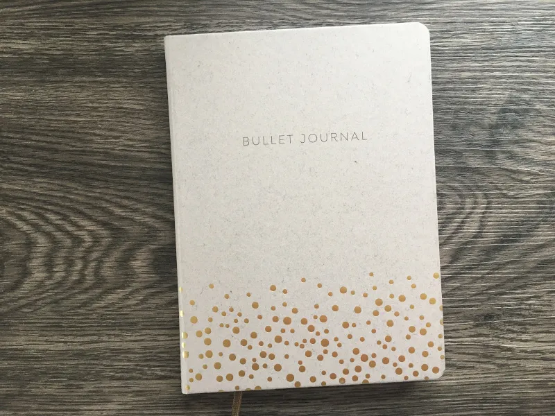 Graues Notizbuch mit Aufdruck Bullet Journal und goldenen Punkten