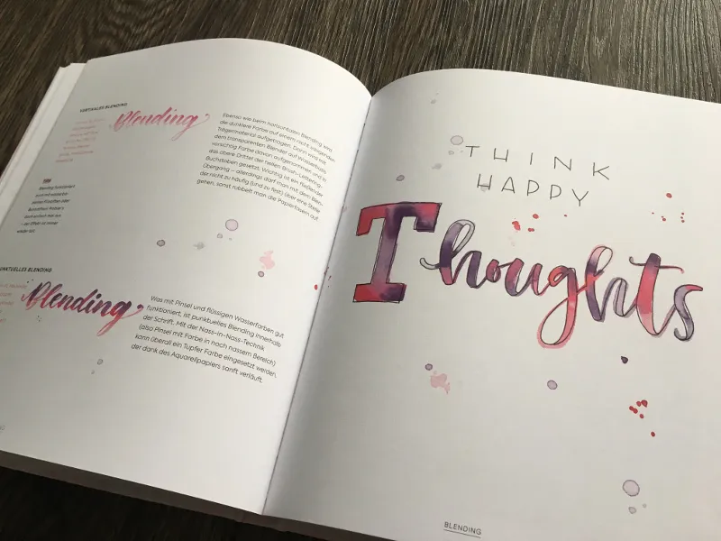Aufgeschlagenes Buch zur Blending-Technik mit Aquarell-Lettering Think Happy Thoughts