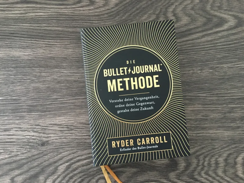Das Buch Die Bullet Journal Methode von Ryder Carroll auf einem Holztisch