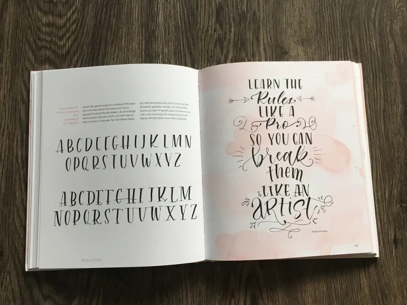 Aufgeschlagenes Handlettering-Buch mit zwei Alphabeten und geschwungenem Zierspruch