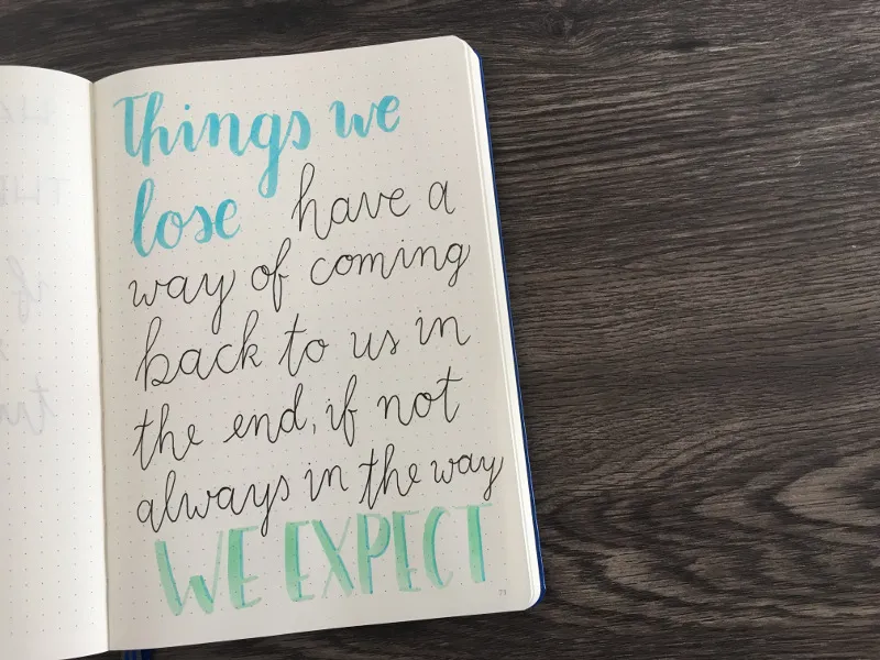 Blaugrünes Brushlettering-Zitat über Verlust auf gepunkteter Seite