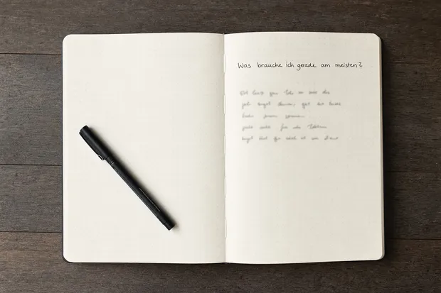 Aufgeschlagenes Journal mit einer handschriftlich eingetragenen Frage und einem schwarzen Fineliner.