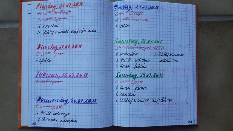 Bunte Tagesübersichten einer Woche in einem karierten Notizbuch, jeder Tag in einer anderen Farbe mit Aufgaben