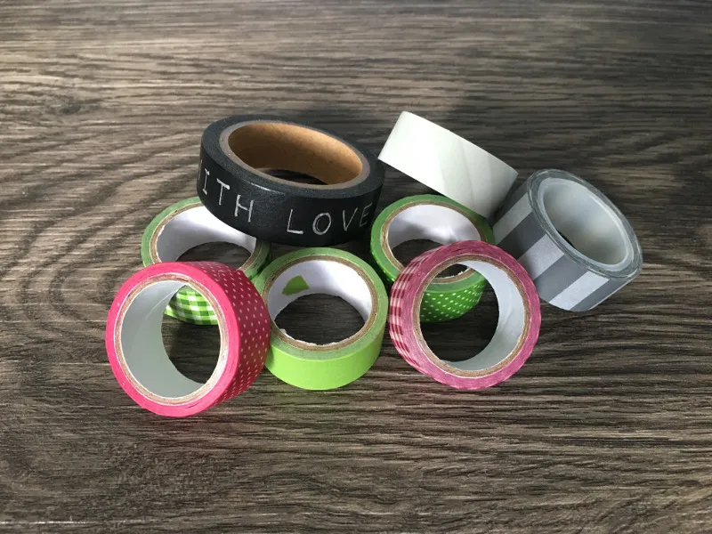 Sammlung bunter Washi-Tape-Rollen auf dunklem Holztisch