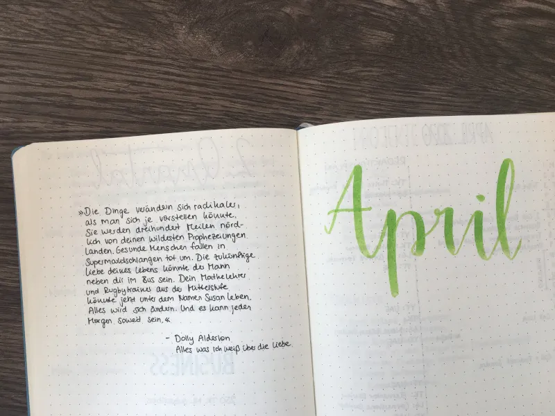 Aufgeschlagenes Bullet Journal mit einem handgeschriebenen Buchzitat von Dolly Alderton links und dem Monatstitel April in grüner Pinselschrift rechts